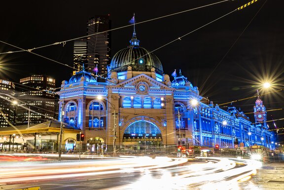 Flinders street station lit up in blue lights at night