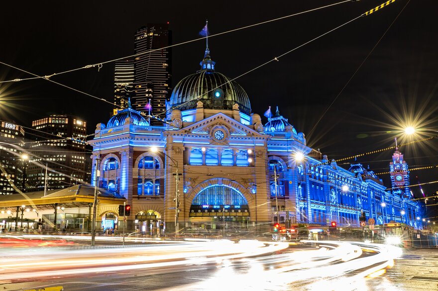 Flinders street station lit up in blue lights at night