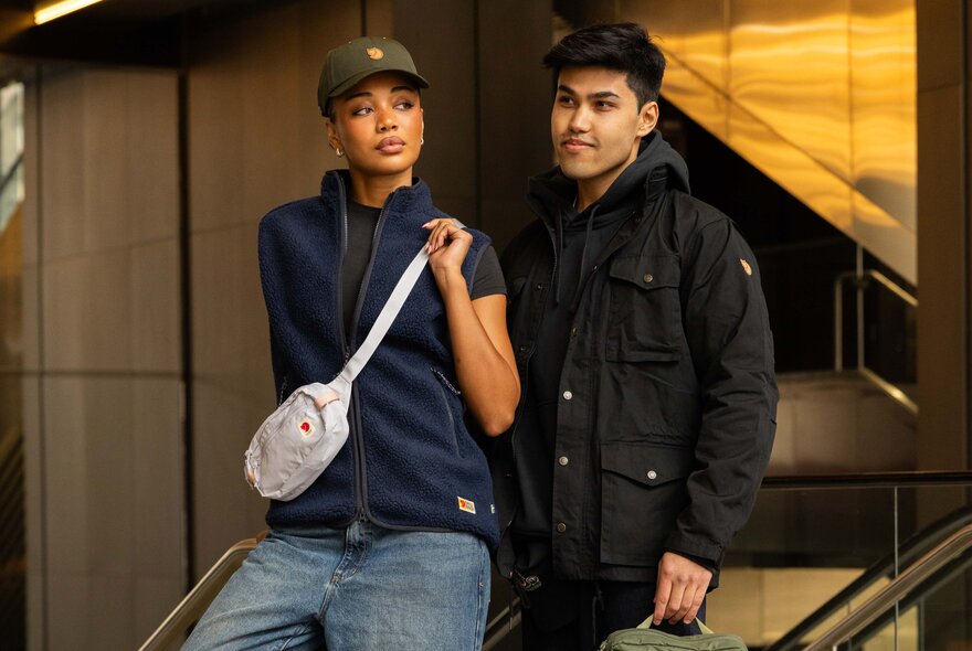 A woman carrying a Fjallraven sling bag standing next to a man.