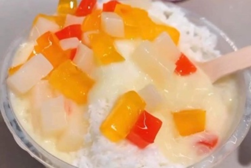 Shaved ice dessert with cubes of jelly garnish on top.