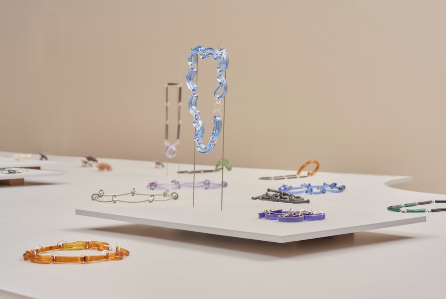 A contemporary jewellery exhibition featuring artistic, structured pieces on white display podiums.