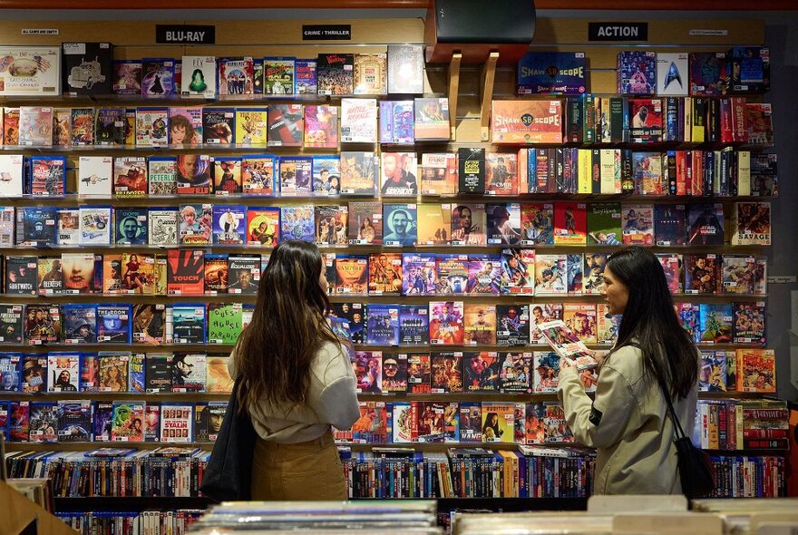 Two women looking at a wall of DVDs and BluRays.