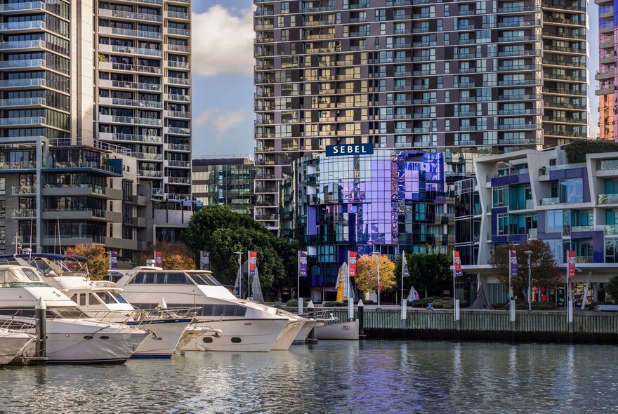 Looking across the Yarra River at the Sebel Hotel Docklands, boats moored to the left. 