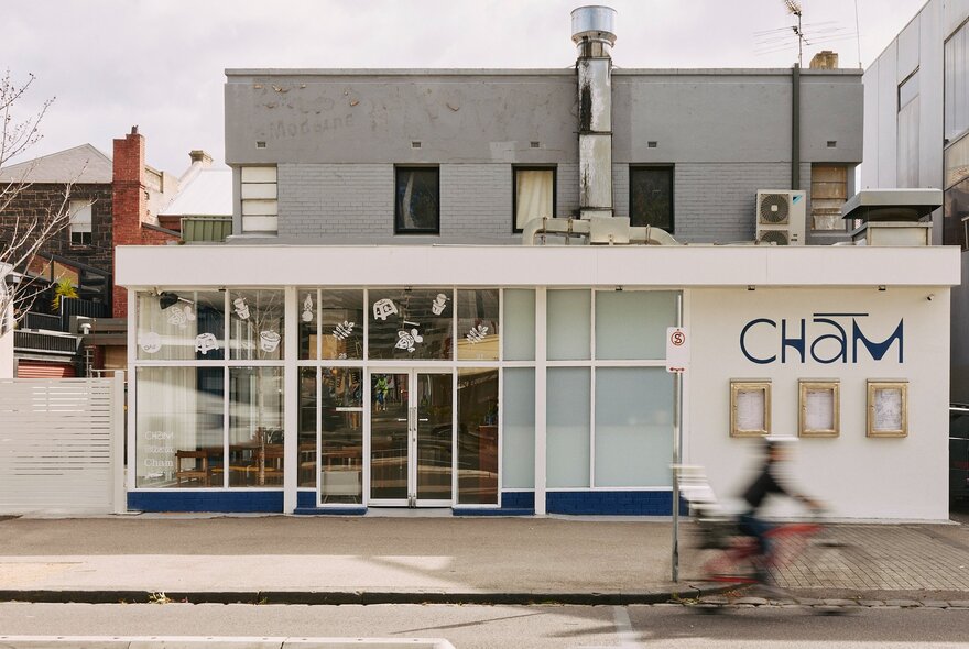 The square-looking shopfront of Vietnamese cafe and restaurant, Cham, with floor to ceiling glass right up to the footpath in front.