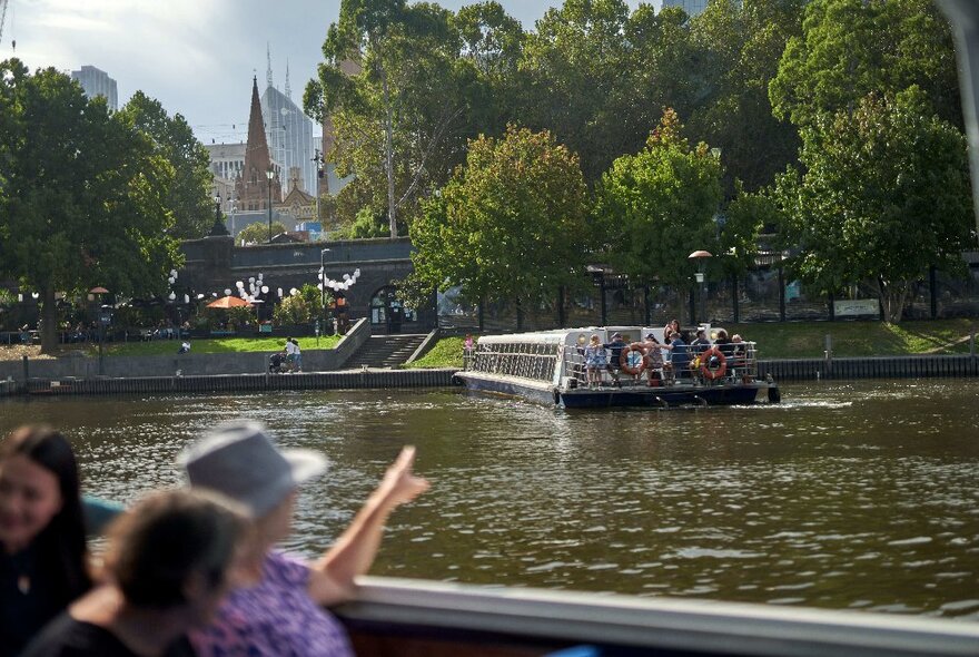 People pointing out featurings on a cruise on the Yarra River. 