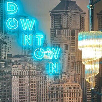 Chandelier and neon signage against wallpaper of city buildings.