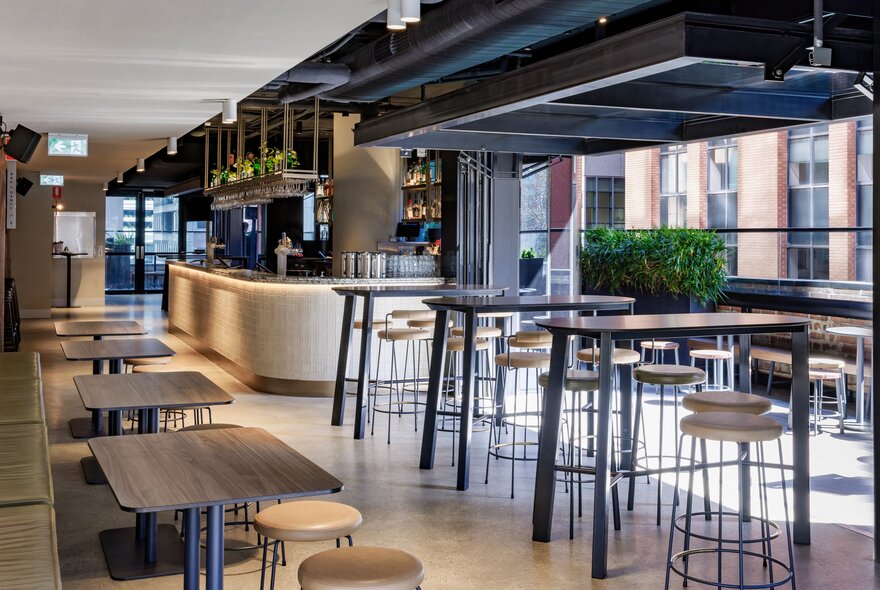 The freshly decorated interior of the Metropolitan Hotel with high stools and tables and banquette seating. 