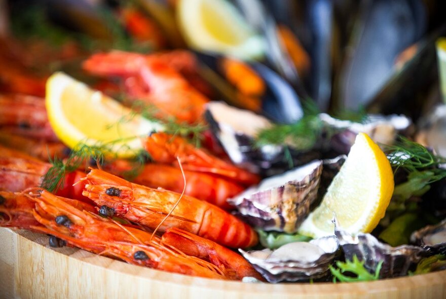 Cooked prawns and oysters on a tray with lemon wedges.