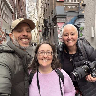Smiling photography teacher and participants standing in a graffitied laneway in Melbourne.