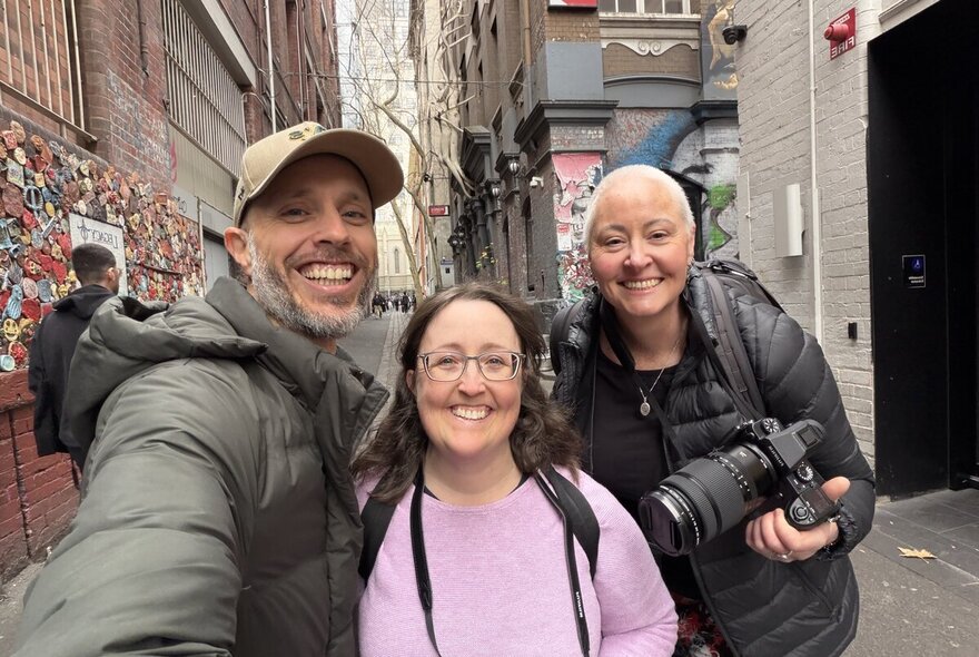 Smiling photography teacher and participants standing in a graffitied laneway in Melbourne.