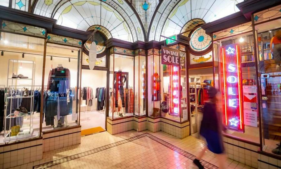 Shops in an arcade with neon signs on the doors