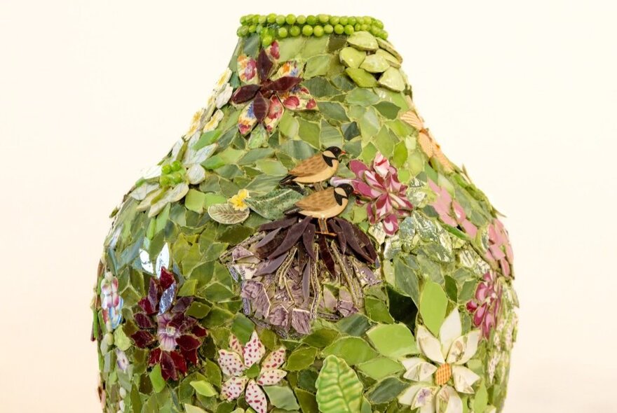 The top of a spring green mosaic vase with flowers on it. 