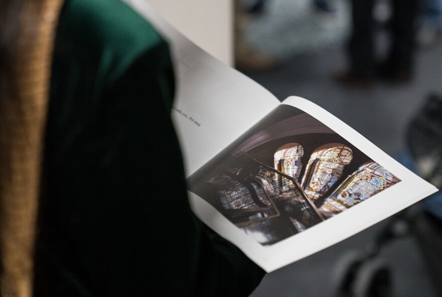 A person looking at an illustrated book or gallery catalogue.