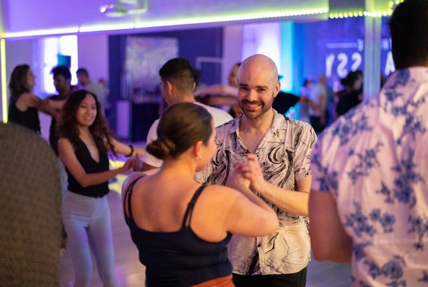 A couple dancing with other couples on a dance floor.