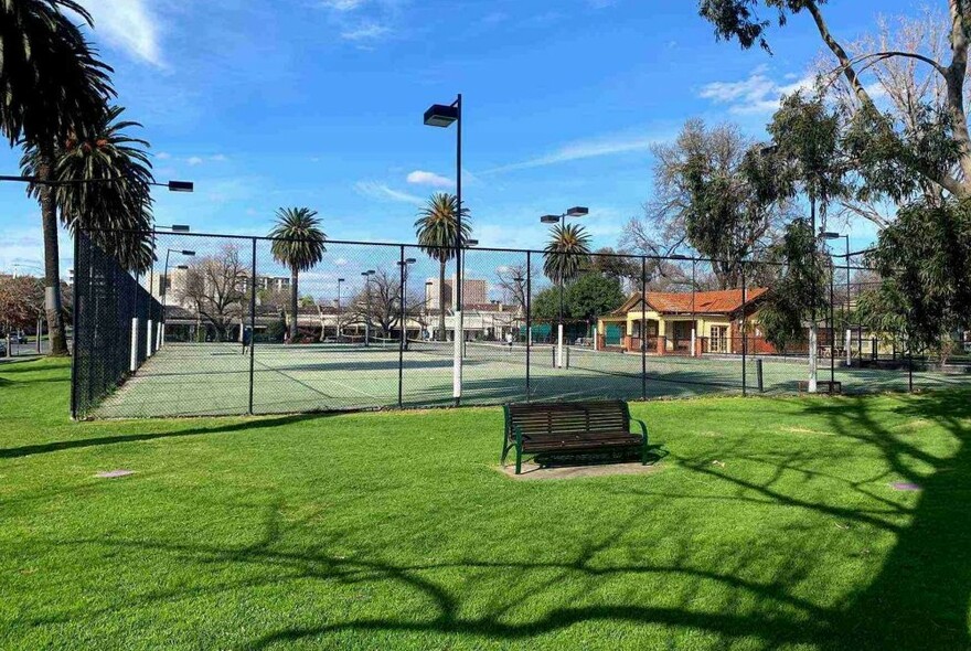 Exterior of the tennis centre showing multi courts and the clubhouse behind a high fence.