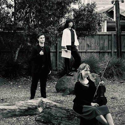 The Changing Wilds Ensemble posed outdoors in a suburban backyard, some with their instruments, in black-and-white.