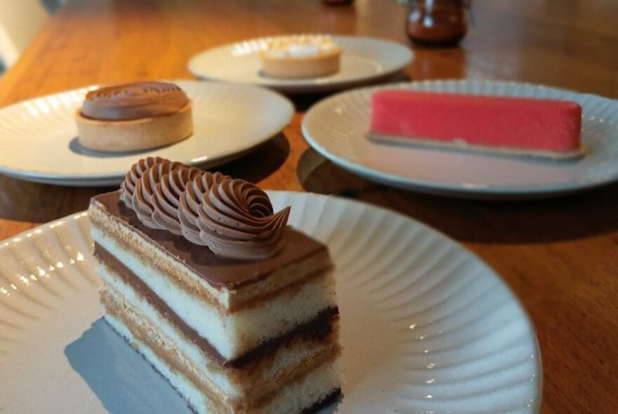 Four sweets on white plates on a table.