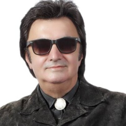 Musician dressed like Roy Orbison with dark glasses, Western shirt and dark hair.