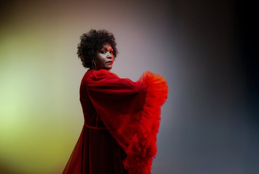 Performer wearing red dress in dramatic yellow and dark lighting.