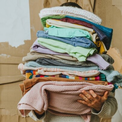 A person carrying a pile of old clothing.