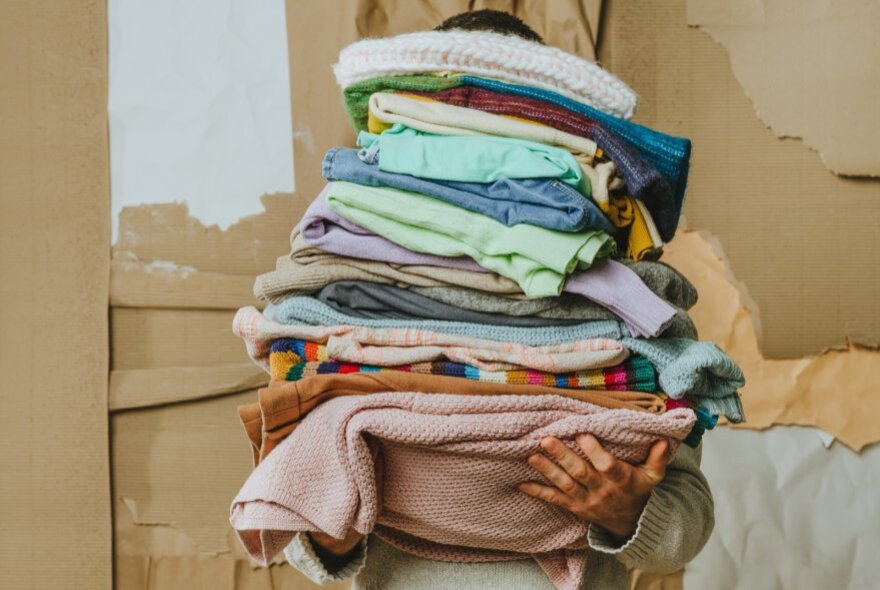 A person carrying a pile of old clothing.