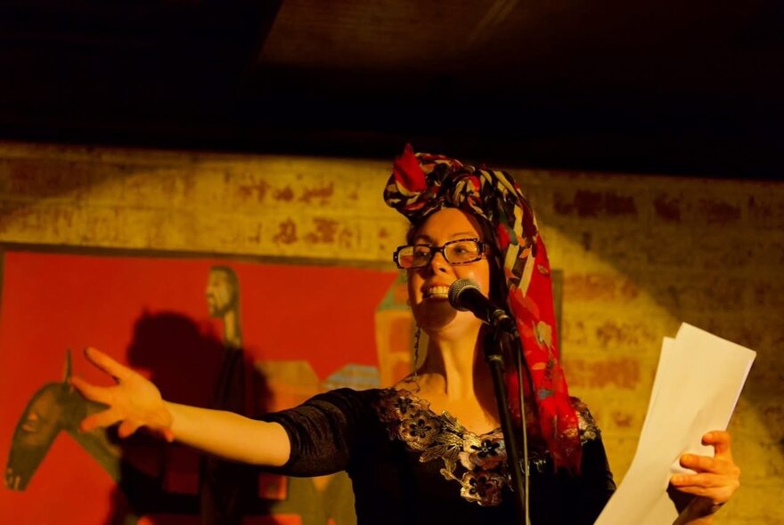 A person onstage performing spoken word poetry or reading into a microphone.