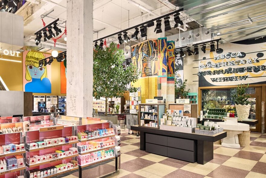 A beauty cosmetics store with wall art, murals, an indoor tree and chequered tiling.