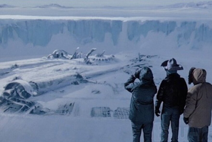 Three men standing in an icy landscape looking at a far-off building.
