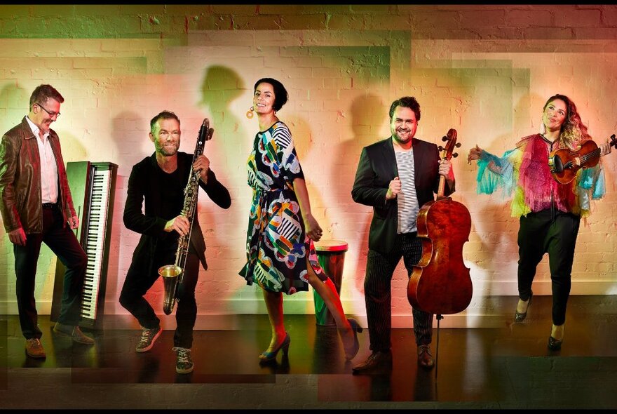 Five musicians from Orchestra Victoria and Ensemble Offspring line up against pastel hued wall with their instruments. 