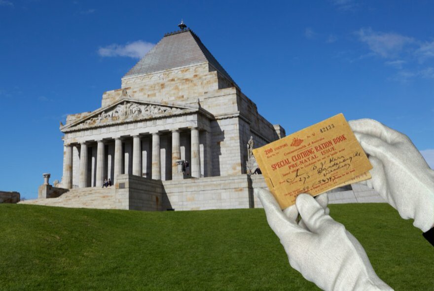 Gloved hands holding a WWII voucher in front of the Shrine of Remembrance.