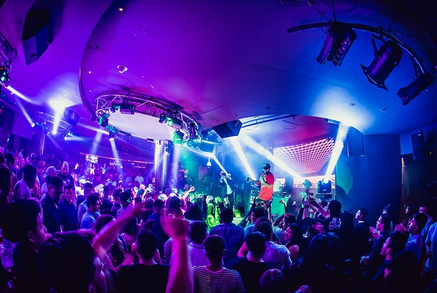 Crowded nightclub bathed in purple and blue light.