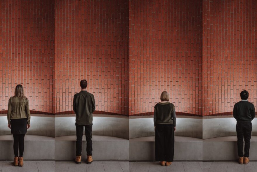 Four people with their backs to the camera, staring at a red tiled wall that forms part of the underground Arden Metro Tunnel station.