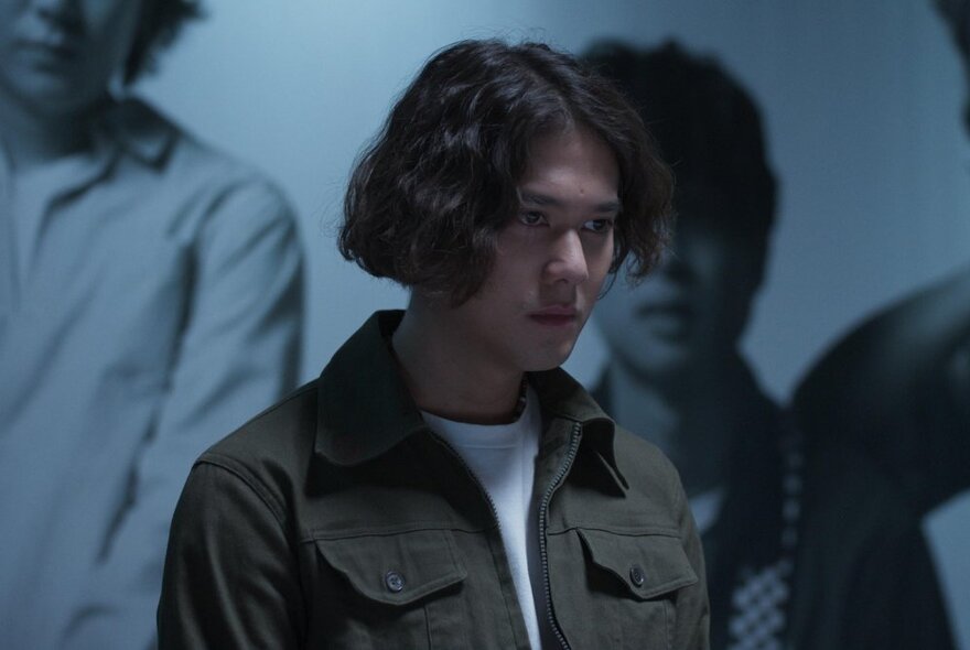 A young man looking thoughtful, has face turned away from the viewer.