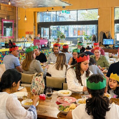 Customers wearing party hats, dining at tables in an indoor venue.