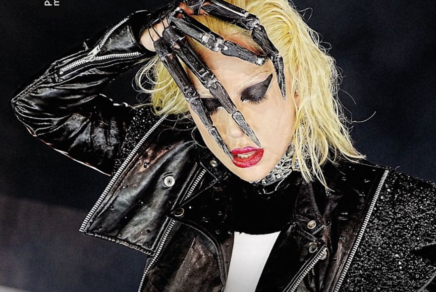 Lady Gaga with her hand over face wearing an Edward Scissorhands glove and a leather biker jacket. 