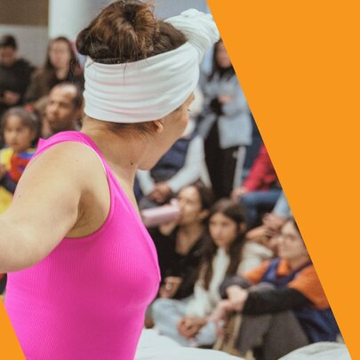 A person performing a dance in front of a seated crowd, as part of a multicultural festival.