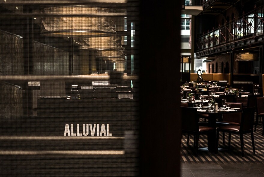 Alluvial signage on panel, with view of restaurant tables to the side.