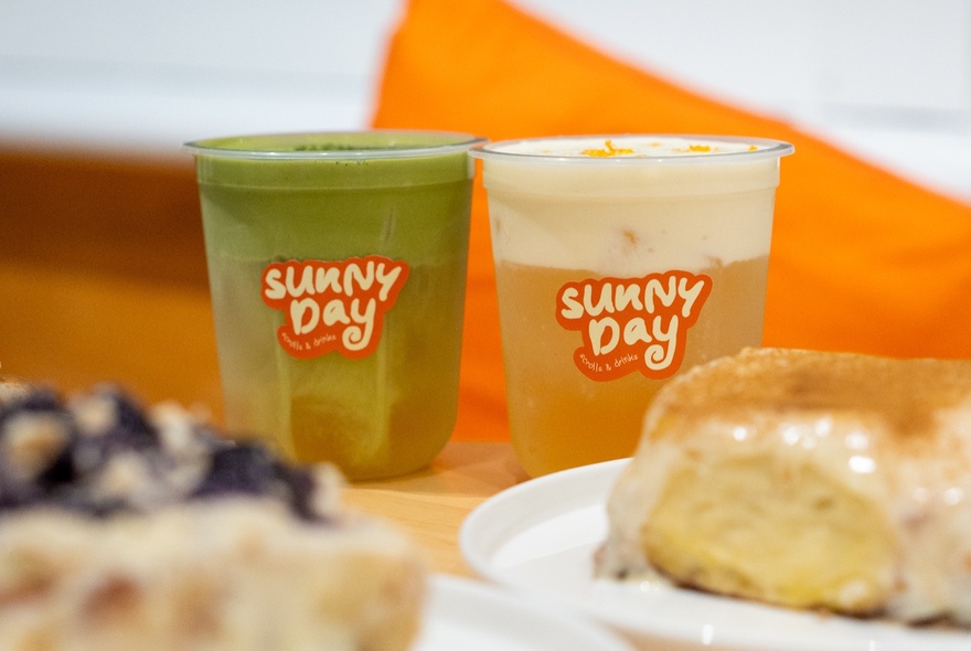 Branded coffee and matcha drinks with iced scrolls on plastic plates.