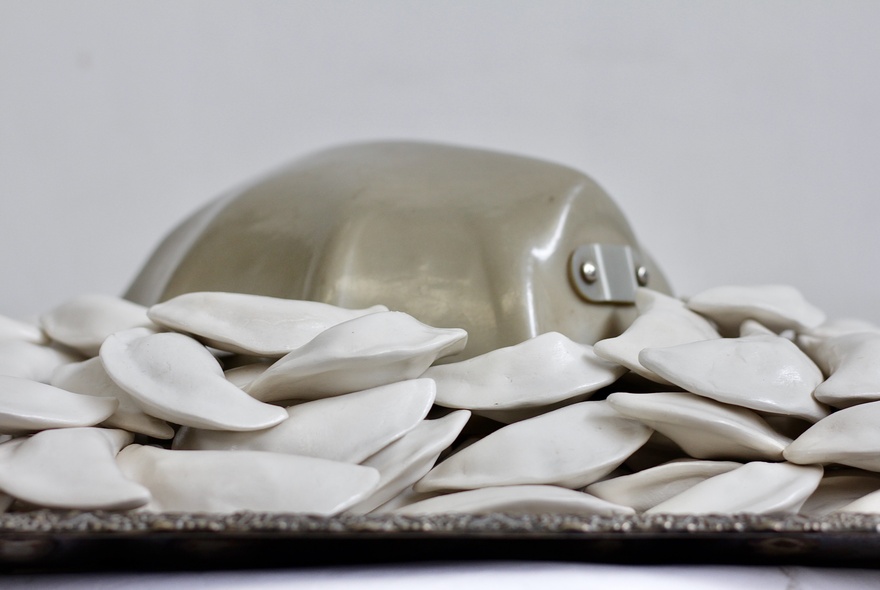 Artwork showing a metal obejct surrounded by  uncooked dumplings.