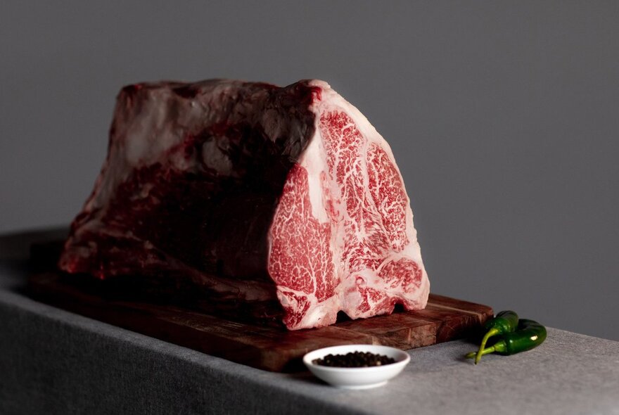 A slab of Wagyu beef on a board with condiments.