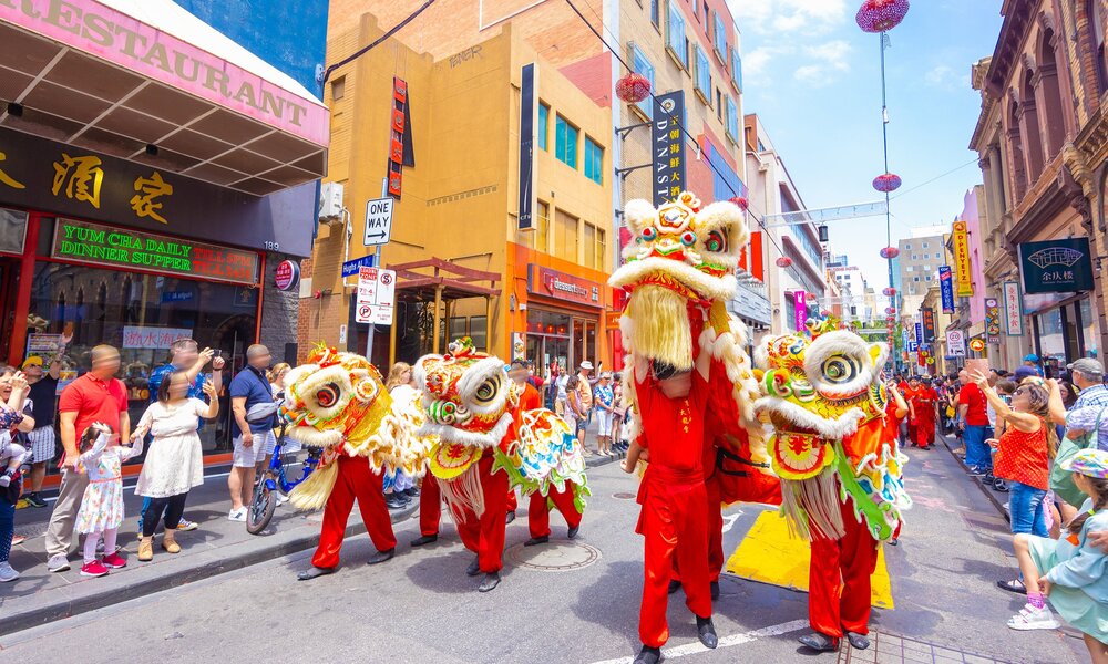 A crowd of people are watching a lion dance performance in Chinatown