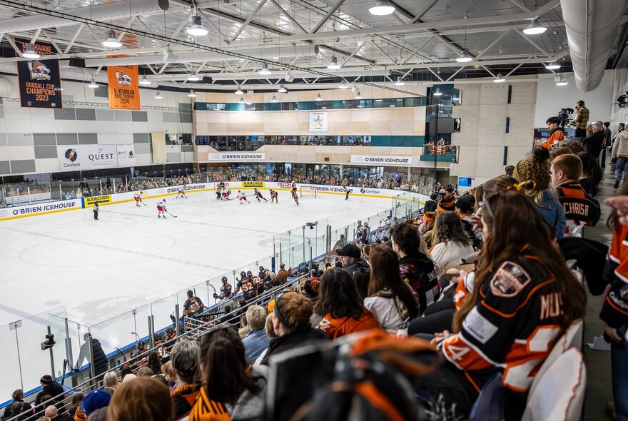 An ice hockey match in progress with spectators in the stands and players on the ice. 