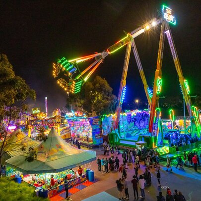 A giant swinging ride with neon lights at a carnival at night.