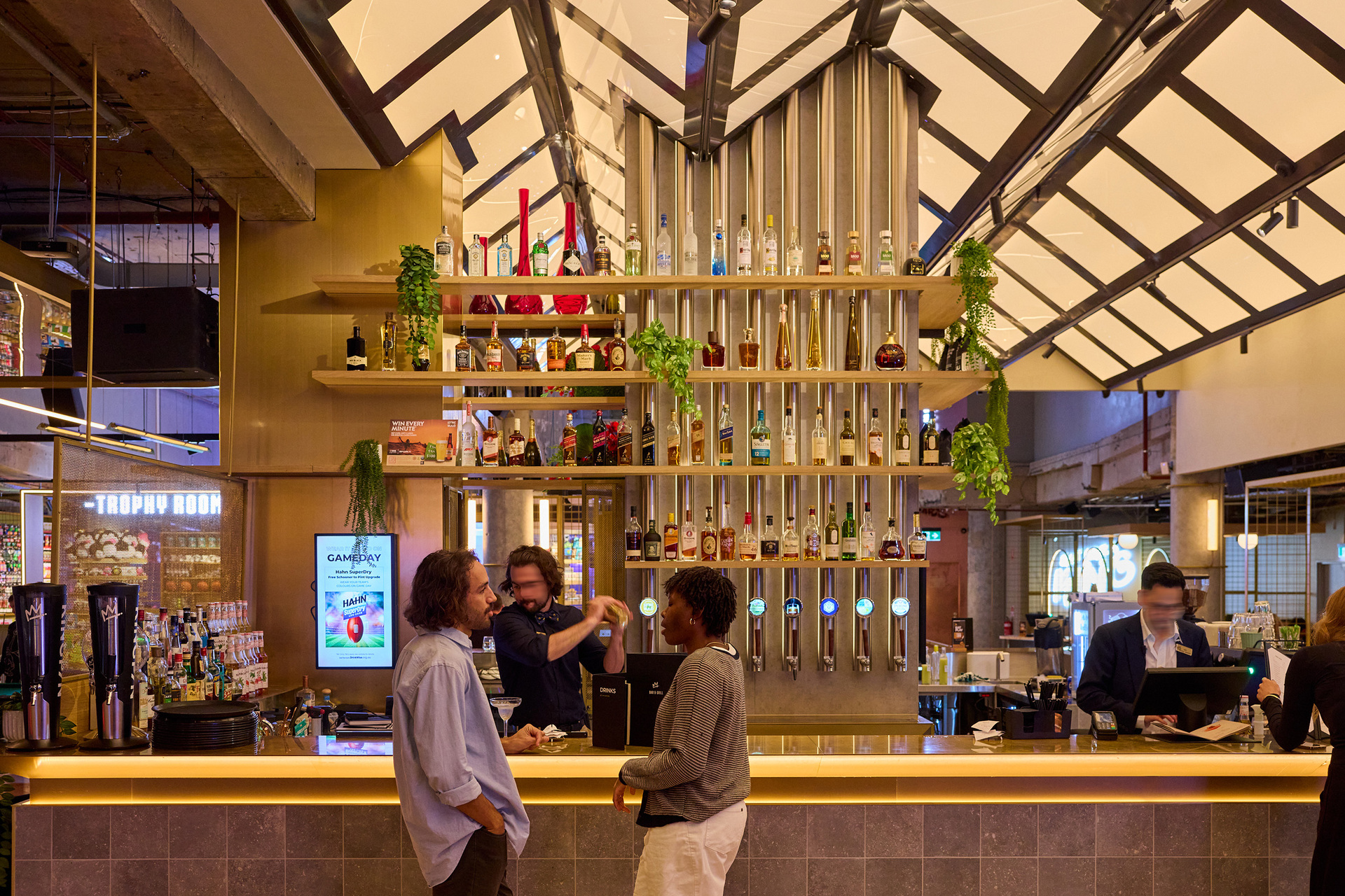 Two friends are standing at a bar a bartender is making them a cocktail