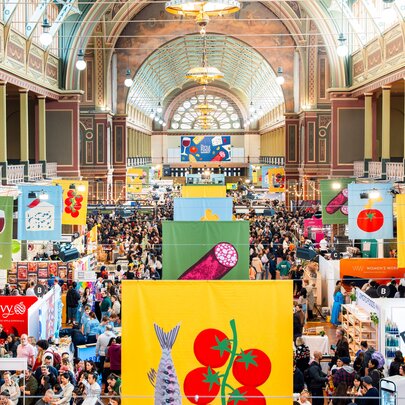 Royal Exhibition Building filled with food stands, signs and people during a food festival event.