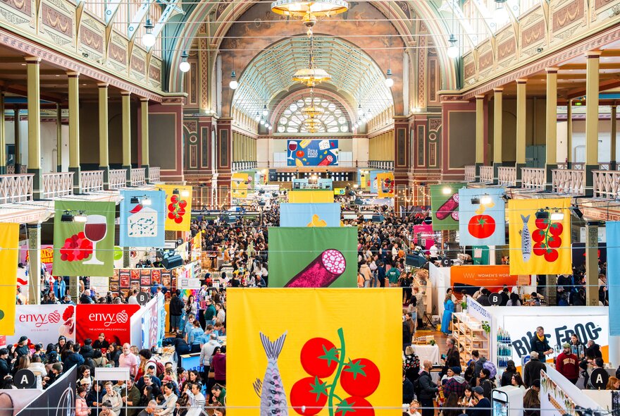 Royal Exhibition Building filled with food stands, signs and people during a food festival event.