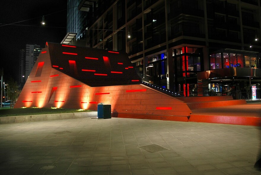 Red stair amphitheatre illuminated at night at Queensbridge Square.