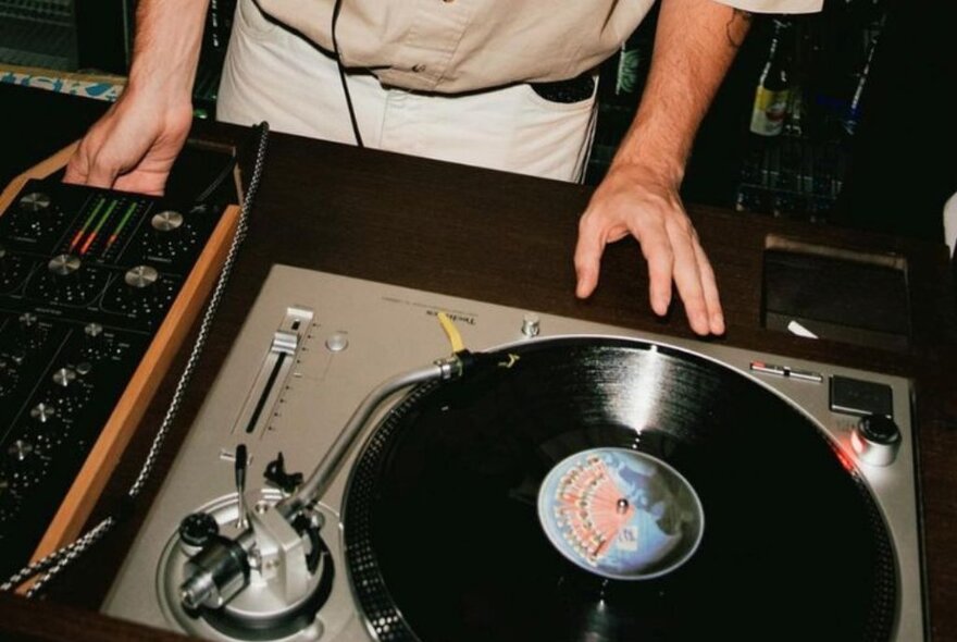 DJ at a turntable with a record playing.