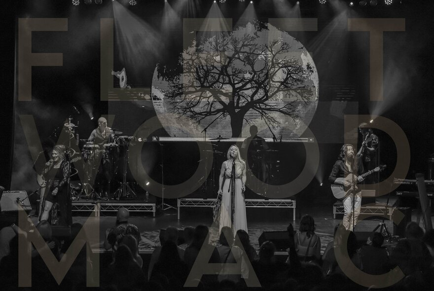 A band of musicians and singers performing live on stage, with very faint large letters spelling out Fleet Wood Mac appearing as a watermark over the black and white image.