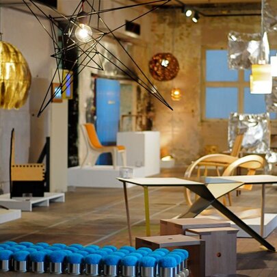 An exhibition space showing lots of light fittings, lamps, desks and ornaments. 